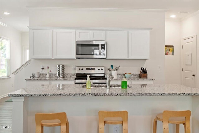 1440 Latham Garden Dr, Wake Forest, NC 27587 - kitchen featuring stainless steel appliances, crown molding, white cabinets, a breakfast bar, and a sink