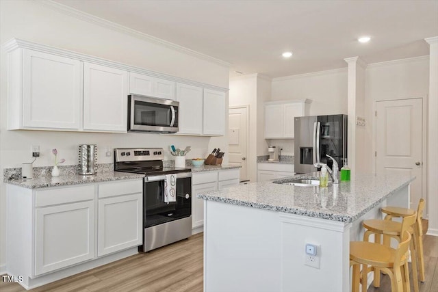 1440 Latham Garden Dr, Wake Forest, NC 27587 - kitchen featuring stainless steel appliances, light wood finished floors, a sink, white cabinetry, and a kitchen bar