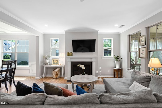 living room with healthy amount of natural light, crown molding, wood finished floors, a fireplace with flush hearth, and recessed lighting