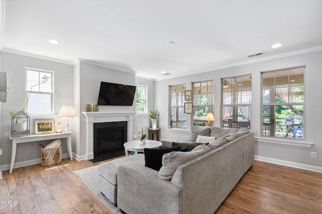 living area with ornamental molding, wood-type flooring, baseboards, a fireplace with flush hearth, and recessed lighting