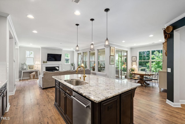 kitchen featuring a sink, a fireplace, crown molding, light wood-style floors, and baseboards