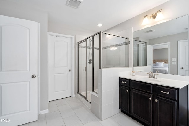 ensuite bathroom with a shower stall, tile patterned flooring, and vanity
