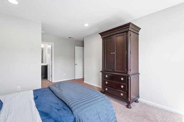 bedroom with baseboards, light carpet, recessed lighting, and connected bathroom