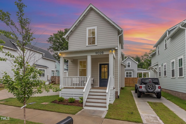 view of front of home with covered porch, a front lawn, and driveway
