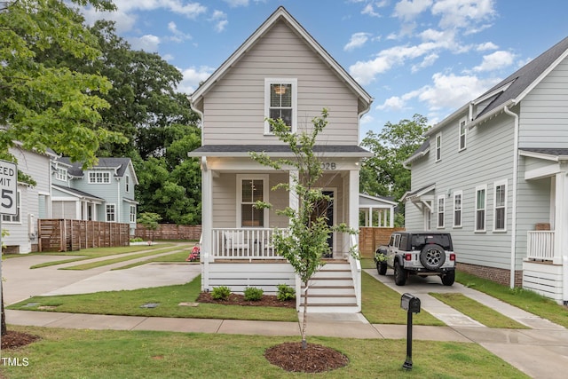 view of front facade with covered porch, a front yard, and concrete driveway
