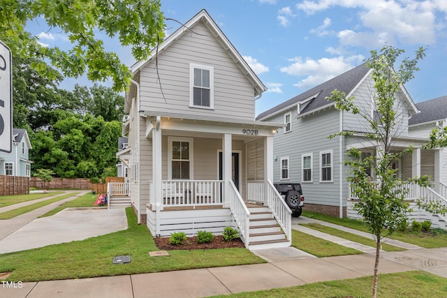 view of front facade with covered porch, a front yard, and stairway