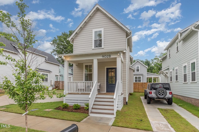 view of front facade with a porch, concrete driveway, and a front lawn