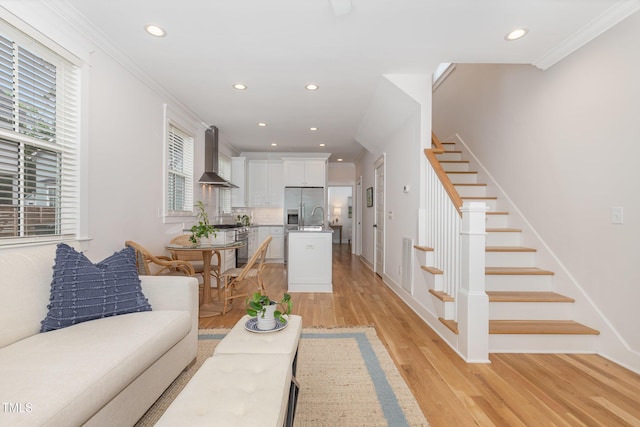 living area with stairs, light wood finished floors, recessed lighting, crown molding, and baseboards