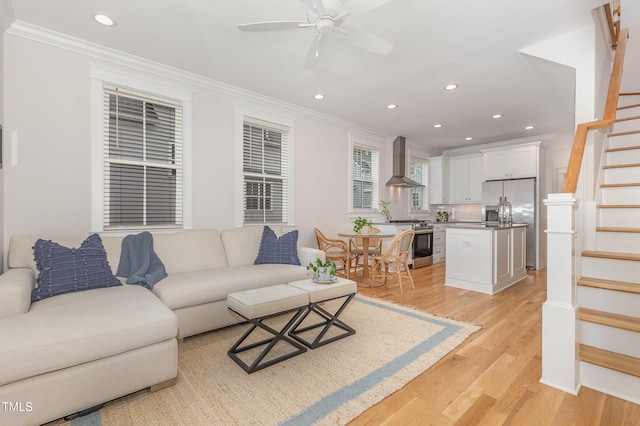 living room featuring crown molding, stairway, a ceiling fan, light wood-style flooring, and recessed lighting