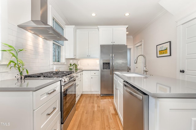 kitchen featuring stainless steel appliances, wall chimney exhaust hood, a sink, recessed lighting, and backsplash