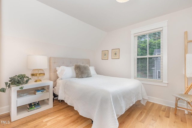 bedroom featuring wood finished floors, vaulted ceiling, and baseboards