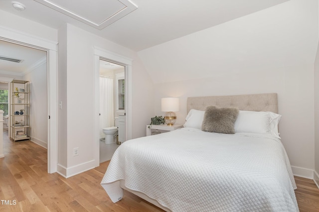 bedroom with light wood-style flooring, baseboards, ornamental molding, and ensuite bath