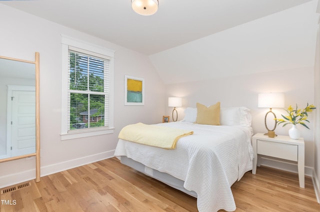bedroom with lofted ceiling, baseboards, and light wood-style flooring