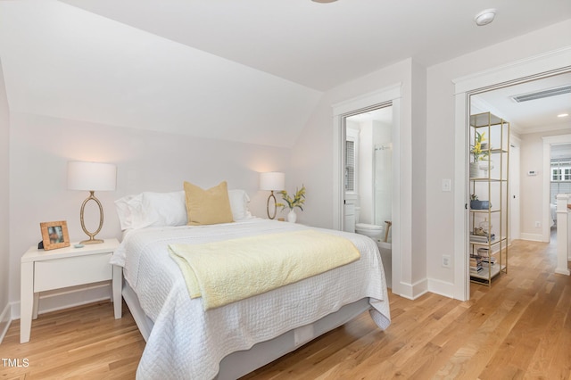 bedroom with light wood-style flooring, baseboards, connected bathroom, and lofted ceiling