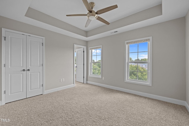 986 Gateway Commons Cir, Wake Forest, NC 27587 - unfurnished bedroom with baseboards, carpet floors, a tray ceiling, a closet, and ceiling fan