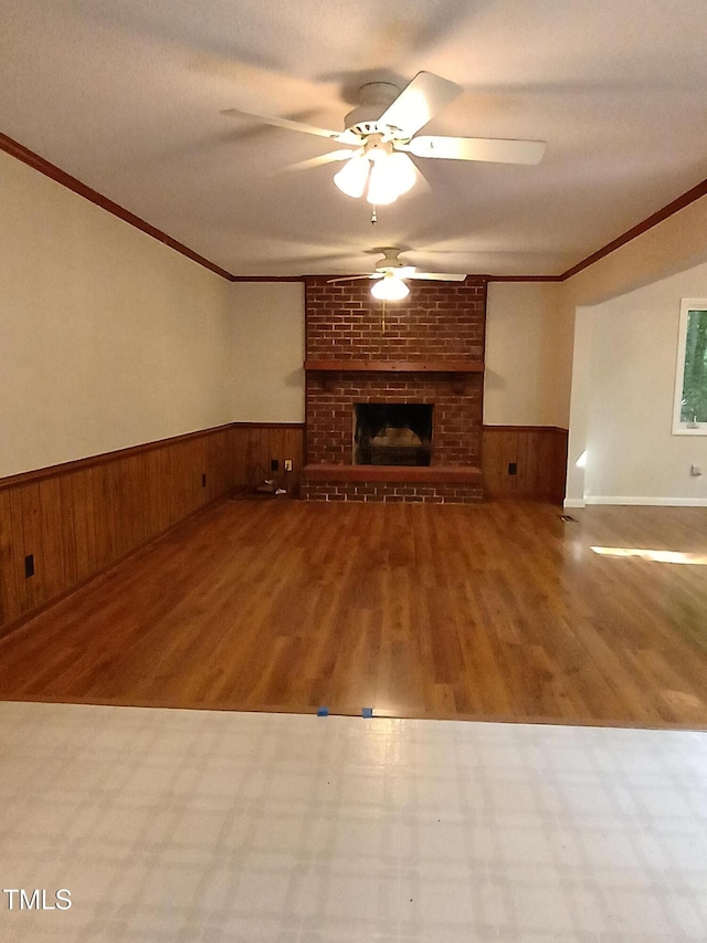 3300 Barnsley Ln, Raleigh, NC 27604 - unfurnished living room featuring ornamental molding, ceiling fan, wood finished floors, wainscoting, and a brick fireplace