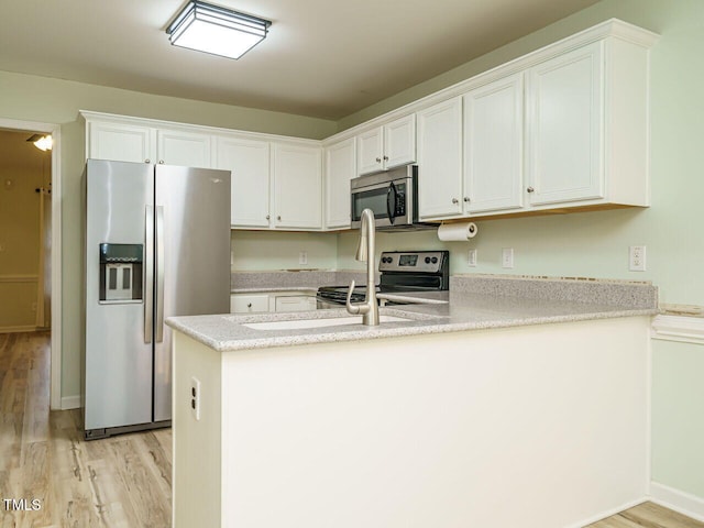253 Middle Landing Dr, Smithfield, NC 27577 - kitchen with stainless steel appliances, light wood finished floors, a peninsula, and white cabinetry