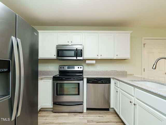 253 Middle Landing Dr, Smithfield, NC 27577 - kitchen with appliances with stainless steel finishes, a sink, light wood-type flooring, and white cabinets