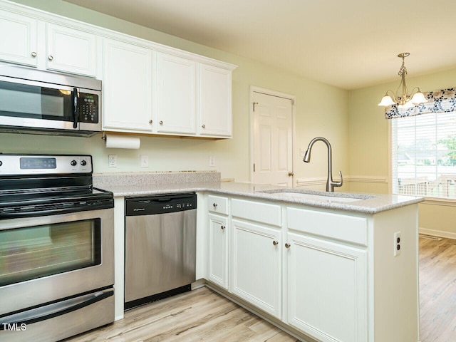 253 Middle Landing Dr, Smithfield, NC 27577 - kitchen with stainless steel appliances, a sink, a peninsula, a chandelier, and light wood-style floors