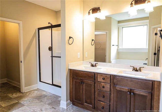 full bath with a shower stall, a bath, baseboards, double vanity, and a spacious closet