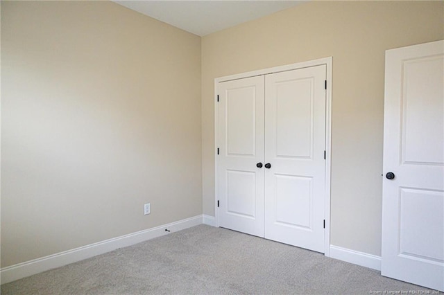unfurnished bedroom with carpet flooring, a closet, and baseboards