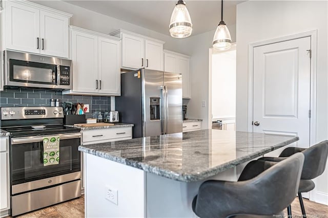 527 Weston Woods St, Raeford, NC 28376 - kitchen with stainless steel appliances, a breakfast bar area, decorative backsplash, a kitchen island, and white cabinets
