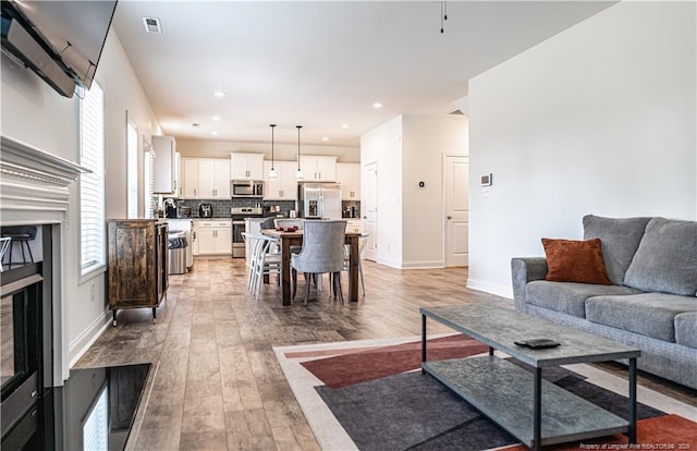 527 Weston Woods St, Raeford, NC 28376 - living room featuring light wood-style floors, baseboards, and recessed lighting