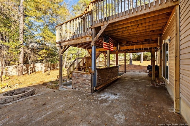 view of patio / terrace with a fire pit, a wooden deck, stairs, concrete driveway, and a carport