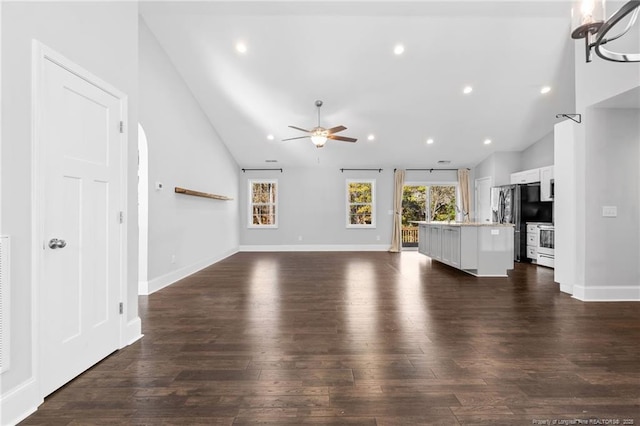 unfurnished living room with a ceiling fan, recessed lighting, dark wood-style floors, baseboards, and high vaulted ceiling