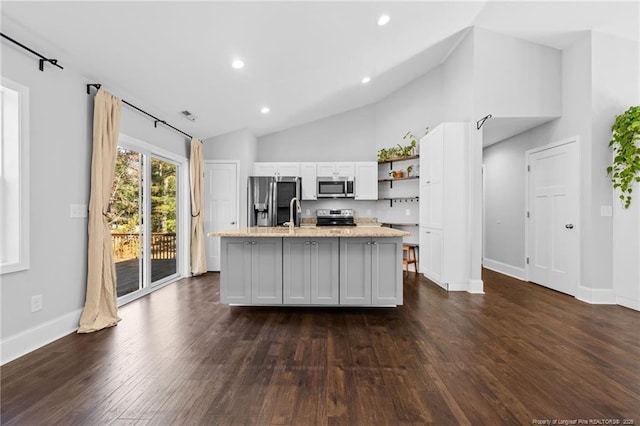 kitchen featuring appliances with stainless steel finishes, open shelves, white cabinetry, vaulted ceiling, and an island with sink