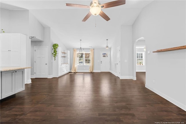 unfurnished living room featuring ceiling fan, dark wood-type flooring, arched walkways, baseboards, and high vaulted ceiling