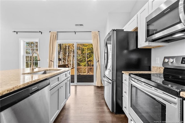 kitchen featuring stainless steel appliances, a sink, dark wood-type flooring, light stone counters, and white cabinets