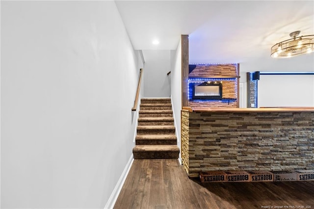 stairs featuring wood finished floors, a bar, and baseboards
