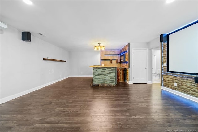 home theater room with dark wood finished floors, a dry bar, and baseboards