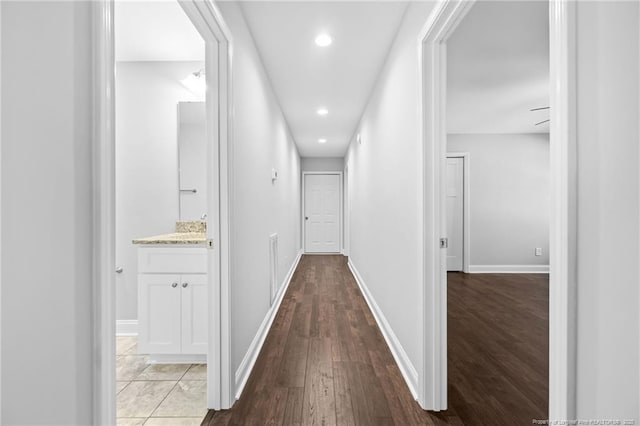 hallway featuring light wood finished floors, recessed lighting, and baseboards