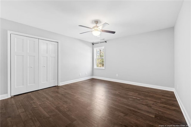 unfurnished bedroom with dark wood-style flooring, baseboards, a closet, and ceiling fan