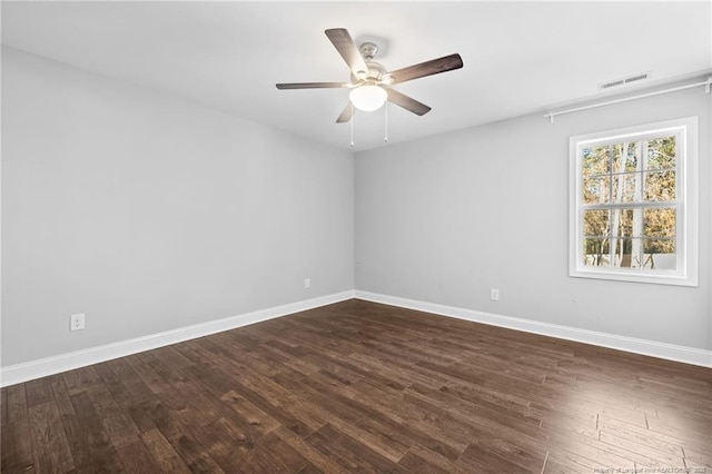 empty room featuring dark wood-style floors, ceiling fan, and baseboards