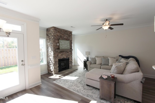 living area featuring healthy amount of natural light, wood finished floors, ornamental molding, a stone fireplace, and ceiling fan