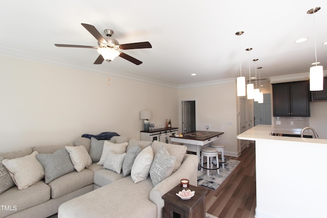 living room with ornamental molding, dark wood-style floors, a ceiling fan, recessed lighting, and baseboards