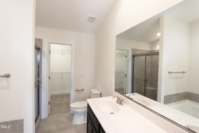 bathroom featuring toilet, a spacious closet, a stall shower, tile patterned floors, and vanity
