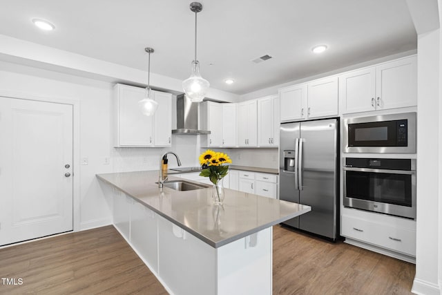 421 Wait Ave Unit 100, Wake Forest, NC 27587 - kitchen featuring appliances with stainless steel finishes, wall chimney exhaust hood, a sink, a peninsula, and dark wood-style floors