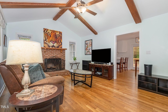 living area featuring light wood finished floors, ceiling fan, and a fireplace