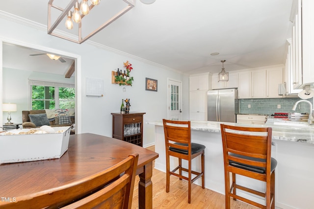 kitchen with freestanding refrigerator, white cabinets, tasteful backsplash, a peninsula, and crown molding