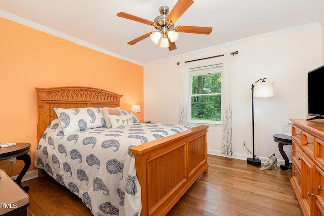 bedroom with wood finished floors, baseboards, crown molding, and a ceiling fan