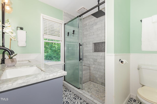 bathroom with a stall shower, wainscoting, toilet, tile patterned floors, and vanity