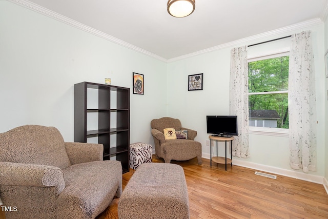 living area with crown molding, light wood-style floors, and baseboards