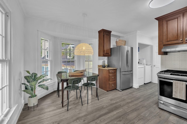 608 Cross Timbers Dr, Durham, NC 27713 - kitchen featuring appliances with stainless steel finishes, under cabinet range hood, washing machine and clothes dryer, crown molding, and light wood-style flooring