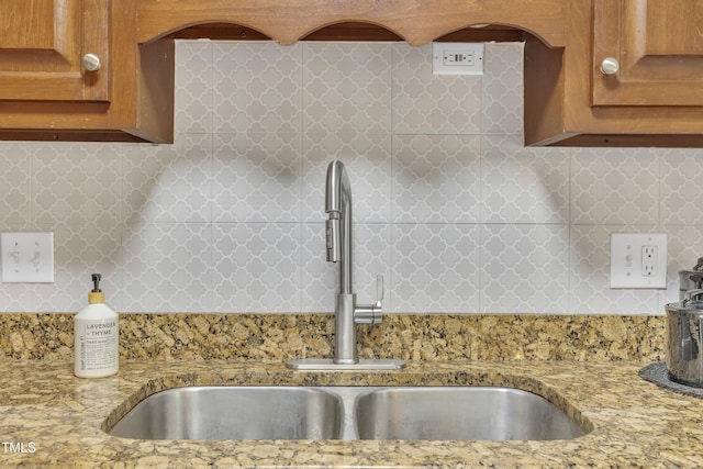 608 Cross Timbers Dr, Durham, NC 27713 - kitchen featuring a sink, brown cabinetry, backsplash, and light stone countertops