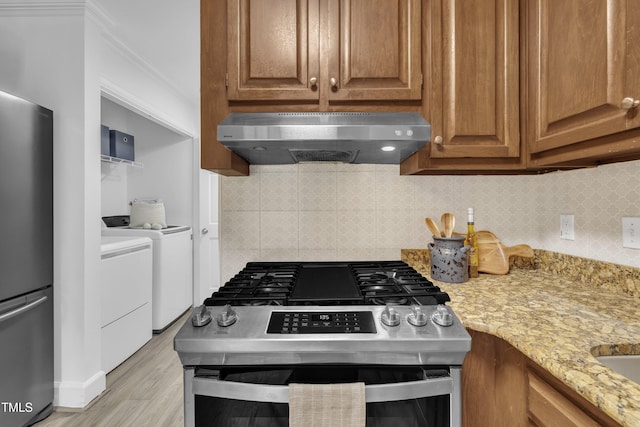 608 Cross Timbers Dr, Durham, NC 27713 - kitchen with appliances with stainless steel finishes, extractor fan, independent washer and dryer, light stone counters, and light wood-style floors