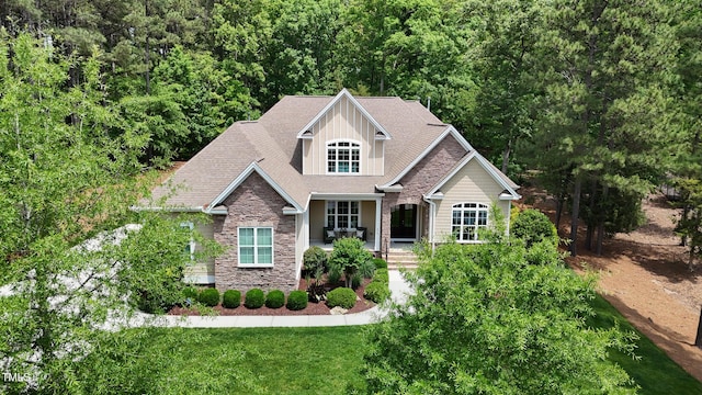 216 Colonial Ridge Dr, Pittsboro, NC 27312 - craftsman-style house featuring stone siding, a porch, a front lawn, and a view of trees
